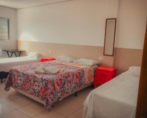 伯迪亚哥Pousada Costa da Riviera的一间卧室设有两张床和一张红色的桌子
