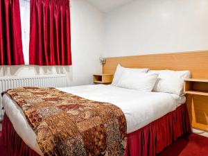 马斯顿格林Royal Square Hotel - NEC & Birmingham Airport的一间卧室配有一张带红色窗帘的大床