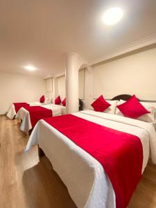 波哥大Hotel Fontibon的配有红色和白色床单的客房内的两张床