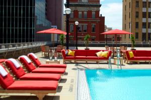 哥伦布哥伦布市中心万丽酒店的屋顶上带红色椅子和遮阳伞的游泳池