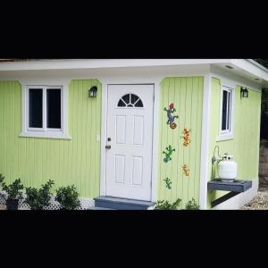 拿骚Budget & Basic in Local Neighborhood, 7min Drive to Downtown Nassau Beach Paradise的绿色的房子,有白色的门和窗户