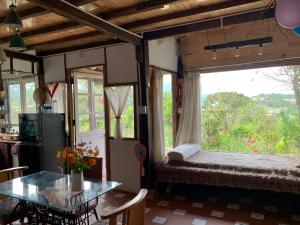 阿普春安Romantic house on a pine hill Dalat的客房设有床、桌子和窗户。