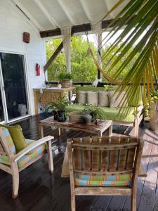 拿骚Hidden Paradise - Cottage的一个带绿色沙发和两把椅子的门廊