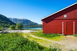 KvaløyaStorjord Farmstay Ranchhouse的旁边一条土路的红色谷仓