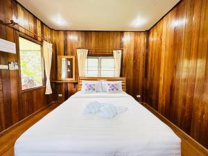 Tok PhromBann Klong Jao Homestay的一间卧室配有一张带木墙的大床
