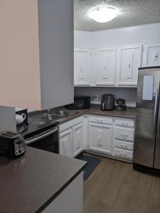 萨斯卡通Bi-Level Suite in Saskatoon的厨房配有白色橱柜和不锈钢冰箱