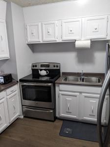 萨斯卡通Bi-Level Suite in Saskatoon的厨房配有白色橱柜、炉灶和水槽。