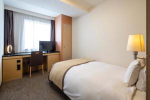 高崎高崎大都会酒店的酒店客房配有一张床和一张书桌及一台电视