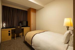 高崎高崎大都会酒店的酒店客房配有一张床、一张书桌和一台电视。