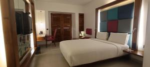 蓬蒂切里滨海大道酒店的卧室配有一张白色大床和电视。