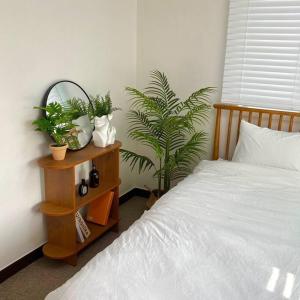 水原市Maison de Haenggung的卧室配有床和植物,位于床头柜上