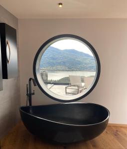 La ChapelleLes Restanques du lac的圆形窗户,浴室内有黑色的浴缸