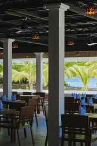 KamadhooAkomadoo Retreat的一间设有桌椅的餐厅,种植了棕榈树