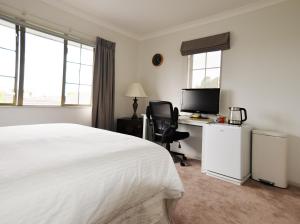 陶朗加Tauranga Homestead Retreat的一间卧室配有一张床和一张带电脑的书桌