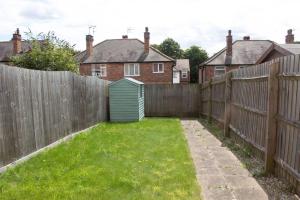 诺丁汉Cosy 2-Bed House in Nottingham的后院设有围栏和绿色棚
