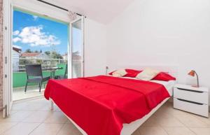 蒂瓦特Apartments Ljubica Tivat的一间白色卧室,配有红色的床和一个阳台