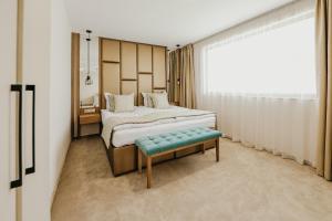 格尔门SPA Hotel Green Park的一间卧室配有一张床、一张长凳和一个窗户。