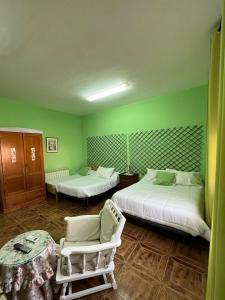 雷阿尔城Hostal Cabañeros的绿色的客房设有两张床和一张桌子及椅子