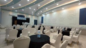 WādhiwareWabi Sabi Resort, Igatpuri的配有桌子和白色椅子的房间,以及舞台