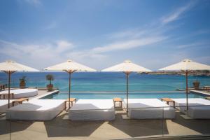 天堂海滩New Paradise Beach Resort的一个带白色床和遮阳伞的游泳池以及大海