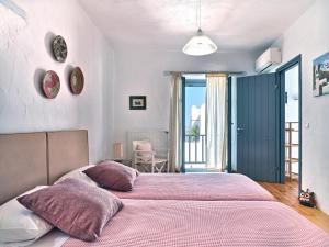 MárpissaAmelie Villa with pool and amazing sea views, Paros的一间卧室配有两张带粉红色床单的床