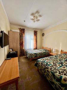 布哈拉阿拉奔酒店的酒店客房设有两张床和一张桌子。