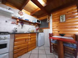 拉安戈斯图拉镇Cabañas con costa al lago, Kalfulafquen的厨房配有木制橱柜和红色桌子。