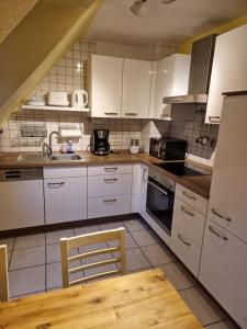 波鸿Ruhrpottbude - Private Ferienwohnung im Herzen des Ruhrgebiets的厨房配有白色橱柜和木桌