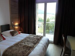 蒙卢伊Hotel et Résidence Le Clos Cerdan的酒店客房设有一张床和一个大窗户
