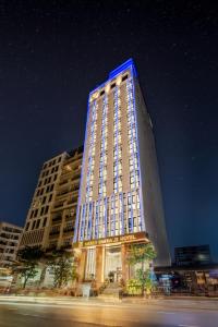 岘港Mercy Emerald Hotel的一座高大的建筑,上面有蓝色的灯光
