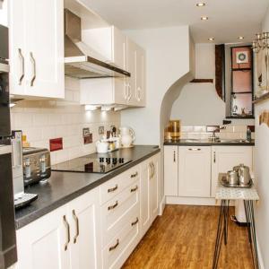 布由德利Whispering Place in the heart of Bewdley的厨房配有白色橱柜和黑色台面