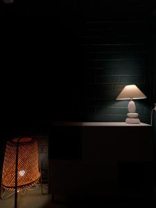 万塔The Rooms Airport - 20Rooms的黑暗的房间里一张桌子,上面有台灯和椅子