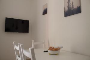 恩波利Appartamento Stella的一张带椅子的白色桌子和墙上的电视