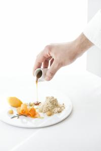 维希Maison Decoret - Relais & Châteaux的手握着勺子,放在盘子里