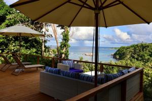 CalibishieBlue Whale Villa - Deluxe Suite的一个带椅子和遮阳伞的阳台,并享有海景。