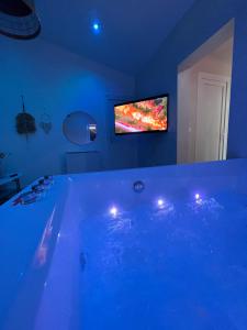 Le Mesnil-Saint-DenisSPA JUNGLE的一间配有电视的客房内的大蓝色浴缸