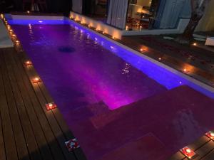 塞米亚克巴厘岛之吻别墅的一座建筑顶部的游泳池,上面有紫色的灯光