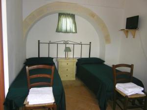 拉泰尔扎B&B Masseria Cappotto的一间卧室配有绿色的床和两把椅子