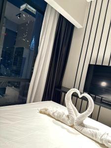 吉隆坡Axon Residence By Leo Suites的白色的床,上面有心形毛巾