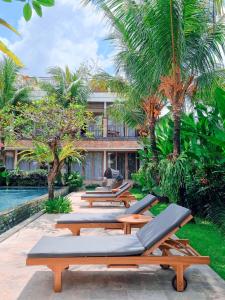 乌布Kahayana Suites Ubud的度假村泳池畔的一排躺椅