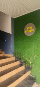 埃尔讷古勒姆kvm rooms and dormitory的一座带绿色墙壁的建筑,设有楼梯和标志