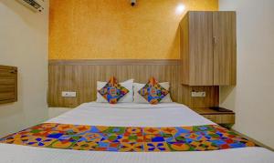孟买FabExpress Prakash Inn的一间卧室配有一张大床和色彩缤纷的毯子
