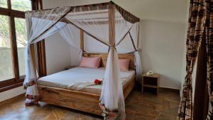 帕杰Bantu Home的卧室配有带粉红色枕头的天蓬床