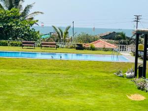 卡兰古特特拉帕莱索度假酒店的庭院中带绿草和长椅的游泳池