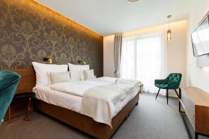 维斯普雷姆西斯托马洛科特酒店的酒店客房设有一张大床和一张绿色椅子。