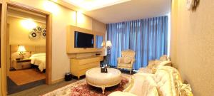 纳杰夫Al Sahla Land Hotel的一间客厅,客厅配有沙发和电视,位于酒店的房间