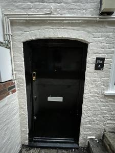 格洛斯特The Cozy Apartment的砖砌建筑中带有标志的黑色门