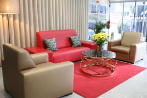 布拉加Hotel Estacão - Braga的大堂设有两把椅子、一张红色的沙发和一张桌子