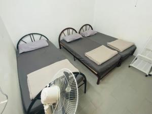日得拉Ruwa Homestay Duo的客房设有两张床和风扇。