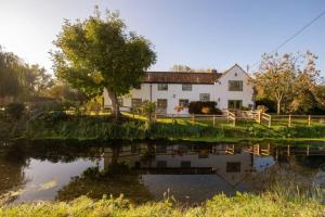 兰波特Peaceful Riverside Five Bed Cottage in Somerset的前面有池塘的房子